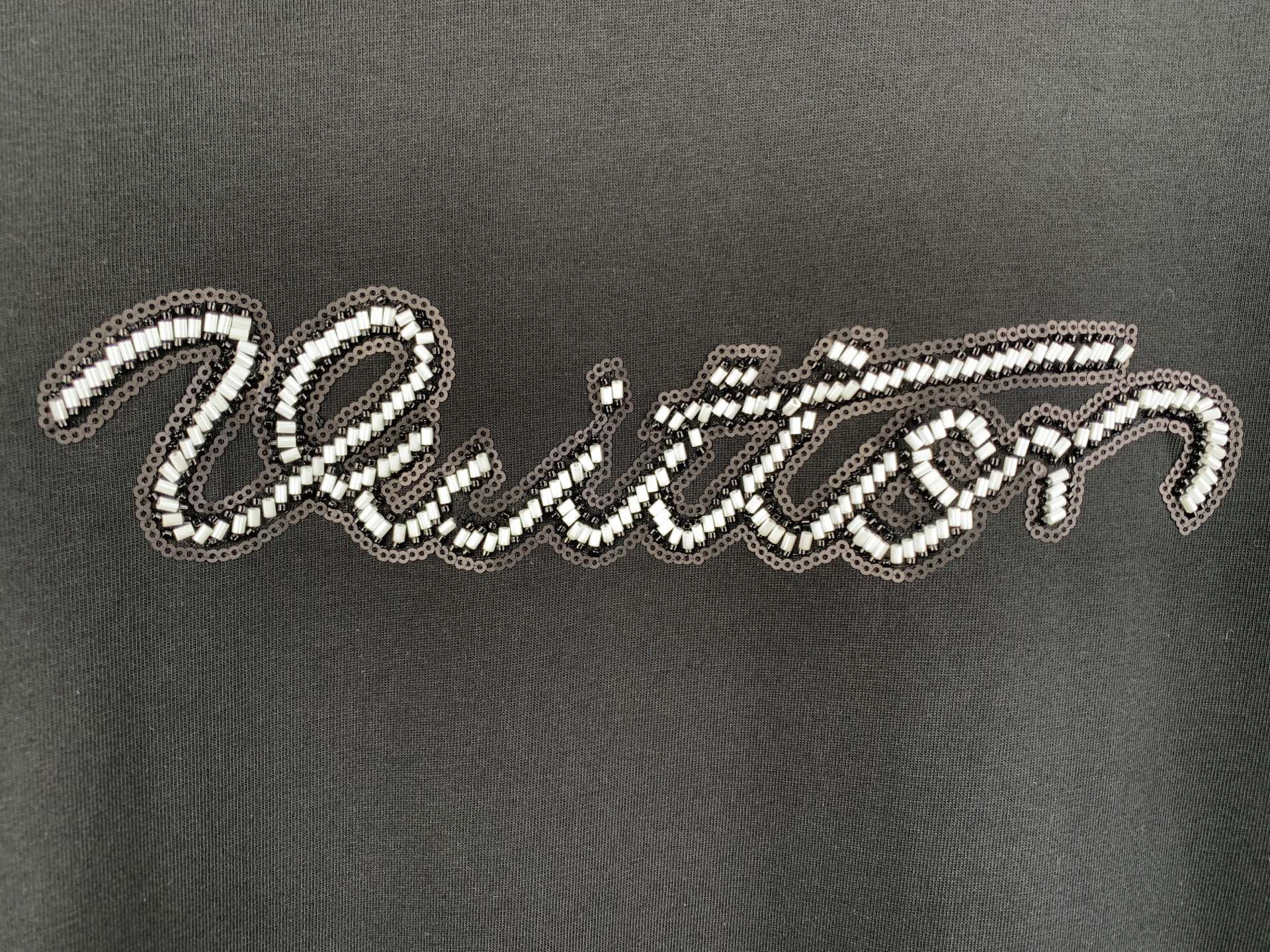 Louis Vuitton rhinestone script logo detail on dark T-shirt