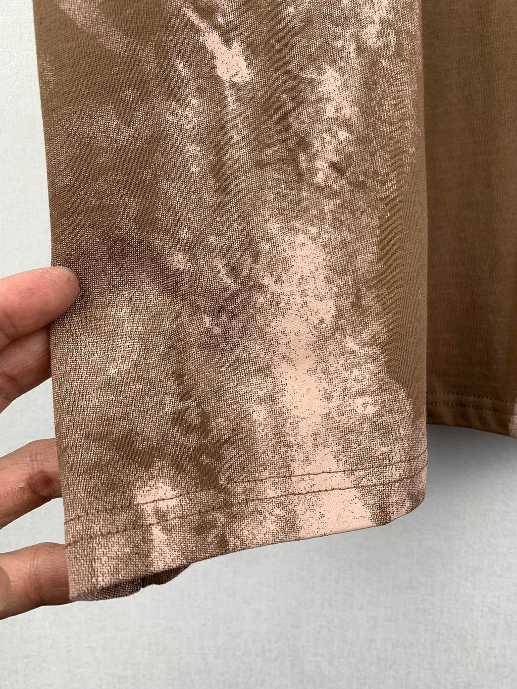 Brown T-shirt bottom hem with white-toned mottled print and stitching