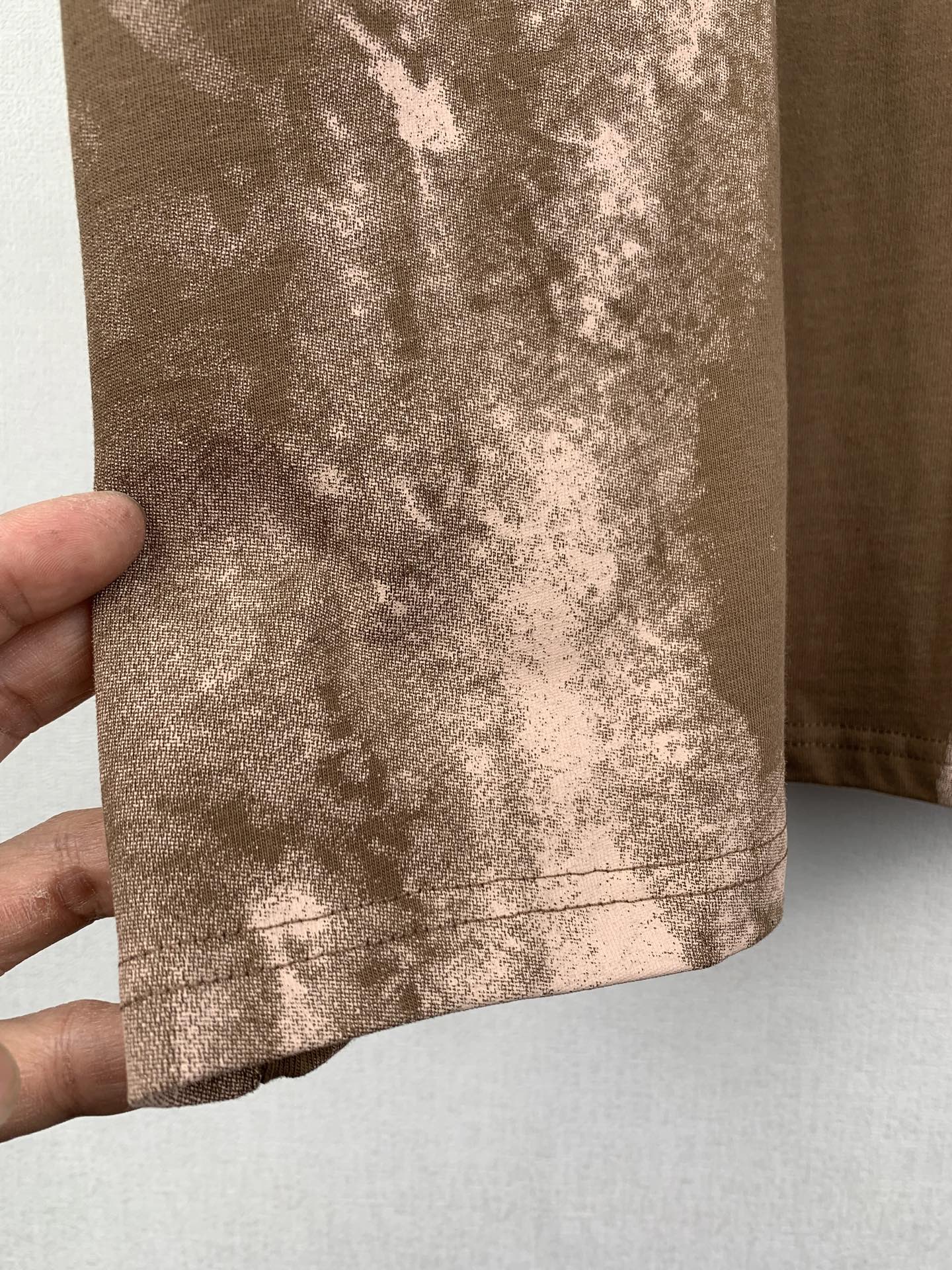 Brown T-shirt bottom hem with white-toned mottled print and stitching