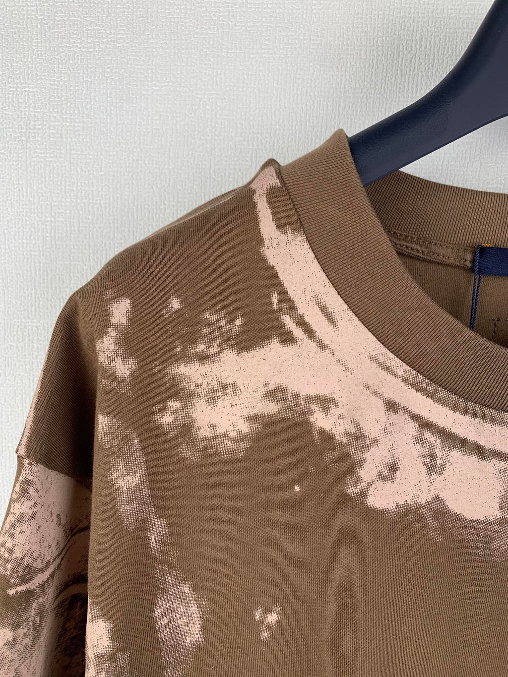 Brown T-shirt with ribbed crew neck and white-toned print across the shoulder