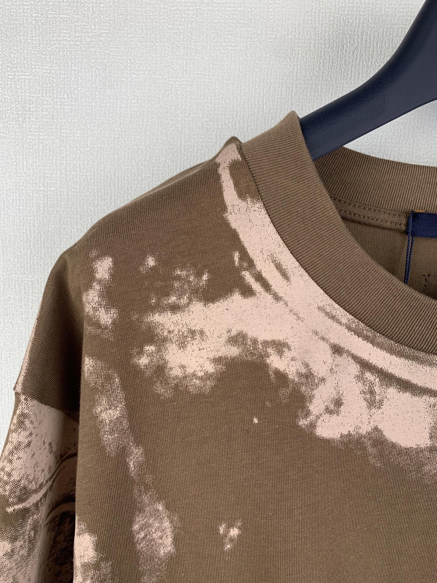 Brown T-shirt with ribbed crew neck and white-toned print across the shoulder