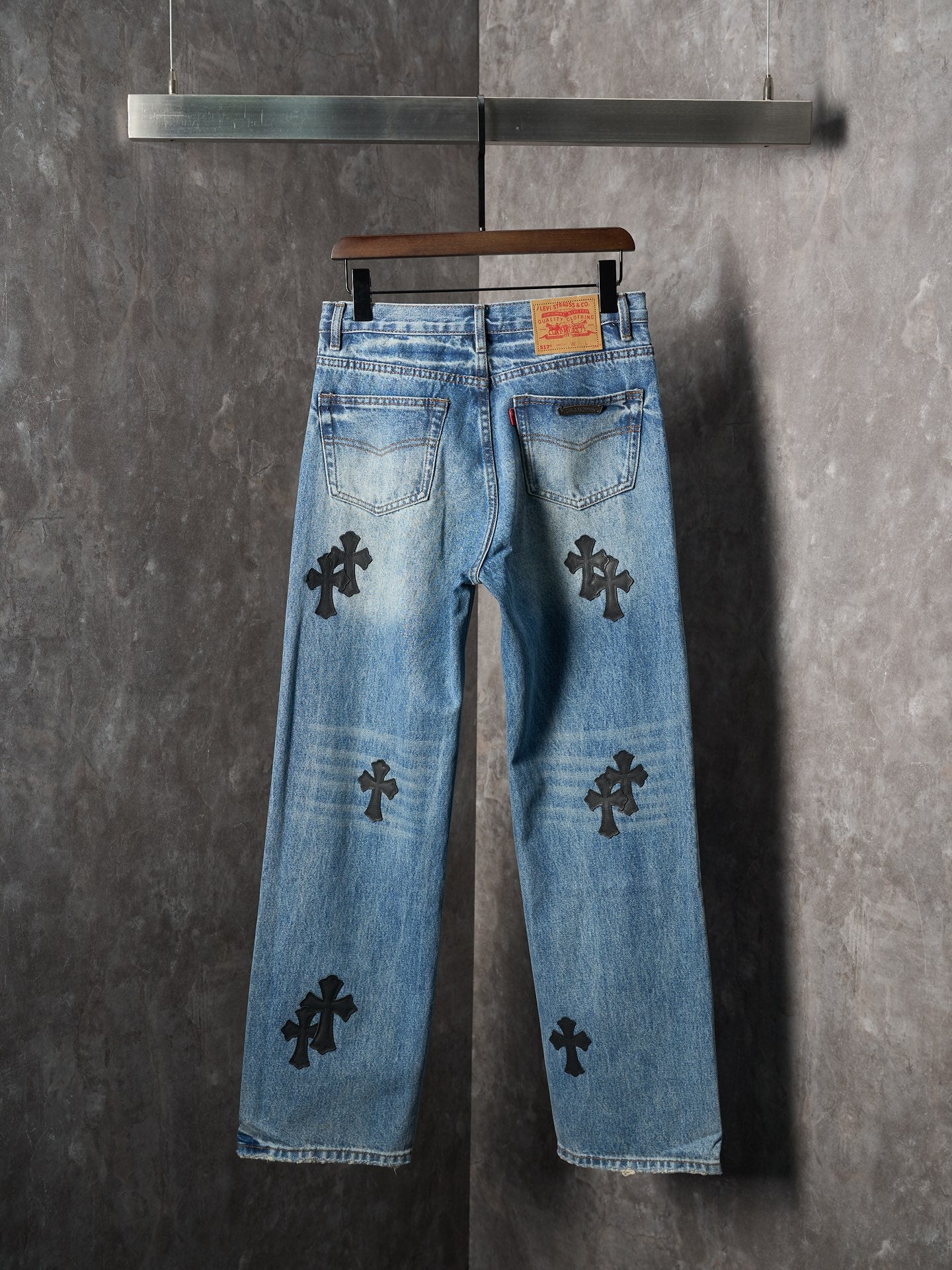 Light blue denim pants with black cross patches, back view