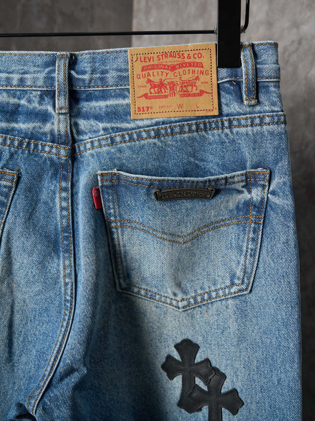 Light blue denim pants close-up: front pocket with black cross patch