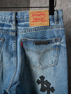 Light blue denim pants close-up: front pocket with black cross patch