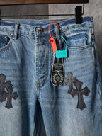 Light blue denim pants close-up: button fly and black cross patches