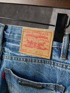 Light blue denim pants close-up: logo patch and belt loops