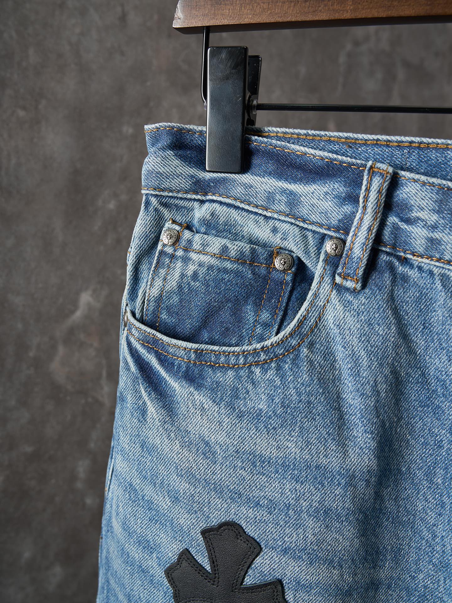 Light blue denim pants close-up: side pocket and black cross patch
