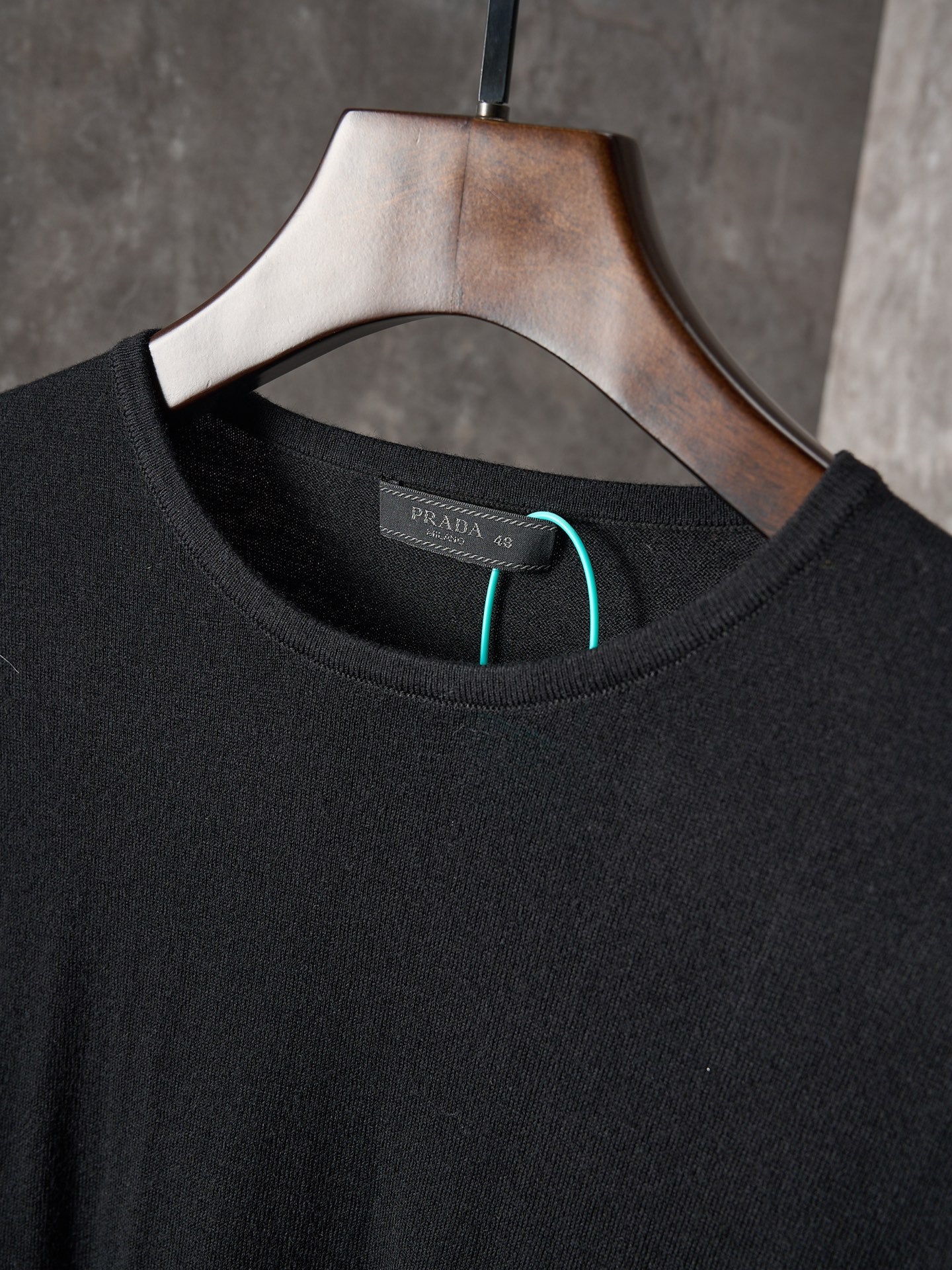 Crewneck collar of black knit sweater with PRADA logo label