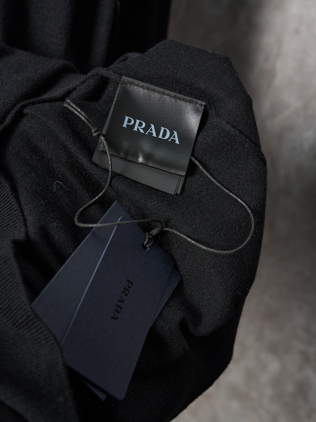 Black knit sweater with PRADA neck label and hanging price tag