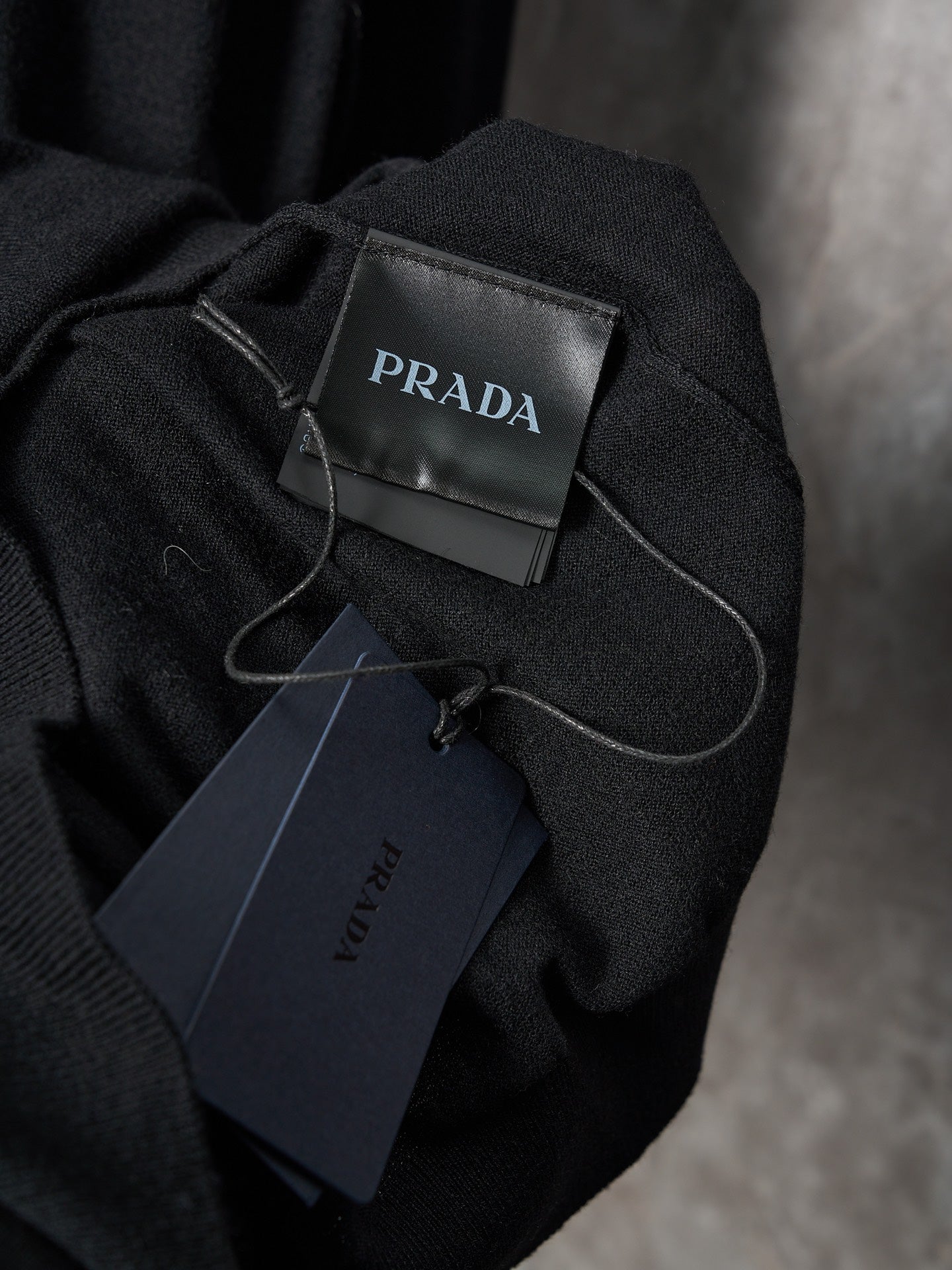 Black knit sweater with PRADA neck label and hanging price tag