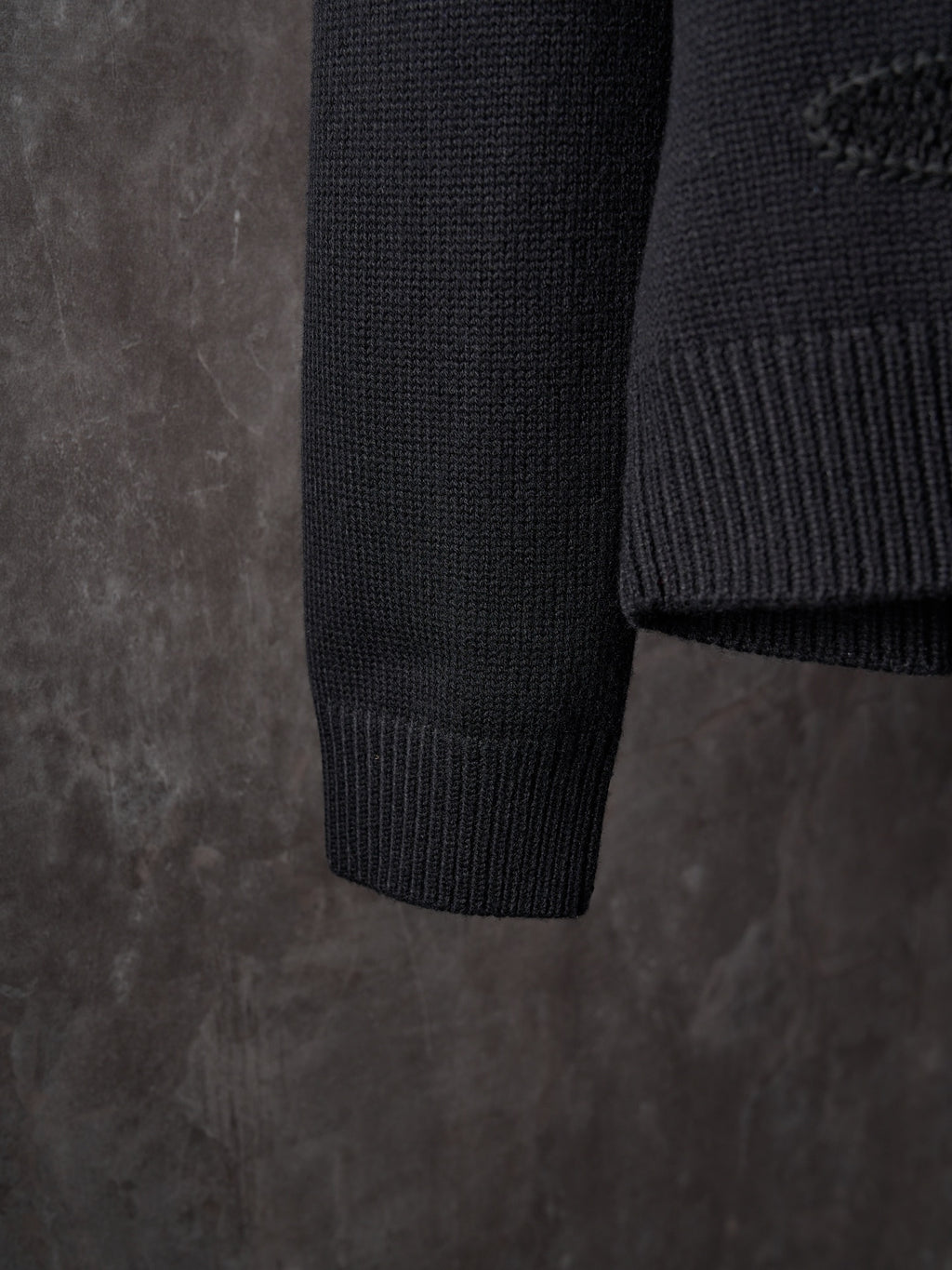 Black knit sweater sleeve cuff and hem in ribbed texture