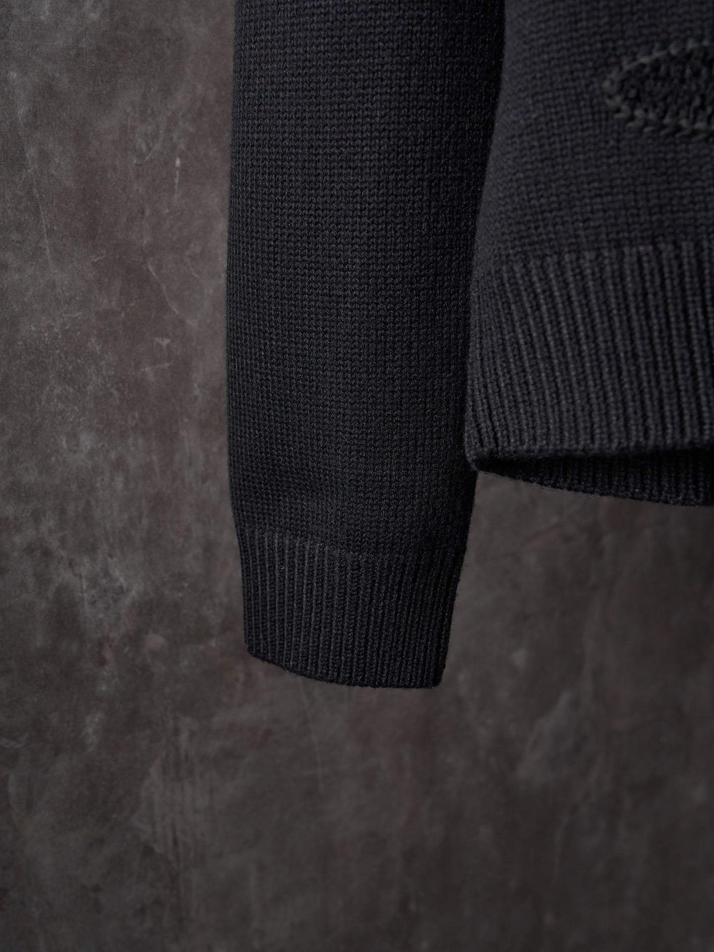 Black knit sweater sleeve cuff and hem in ribbed texture