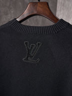 Black knit sweater neckline close-up with embroidered monogram on chest