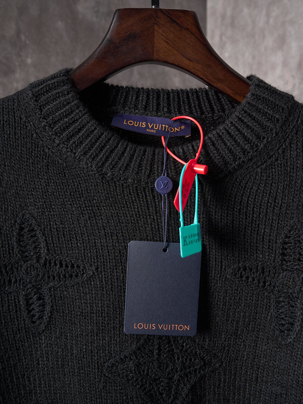 Black knit crewneck sweater with Louis Vuitton logo tag on hanger