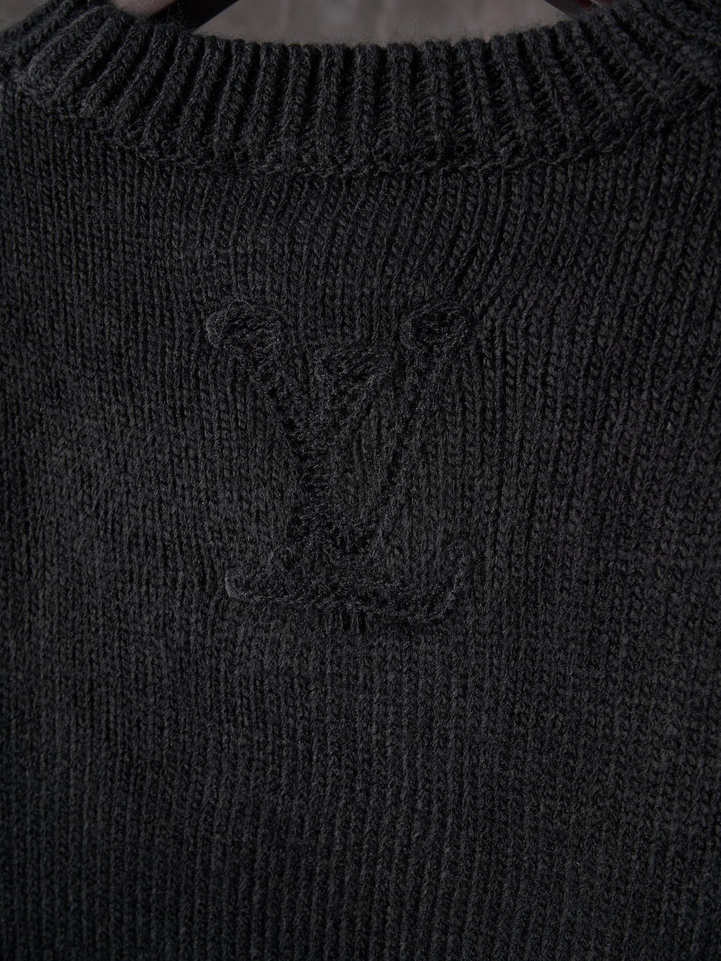 Black knit sweater with central monogram detail and ribbed collar