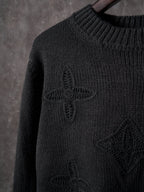 Black knit sweater with raised textured monogram graphic