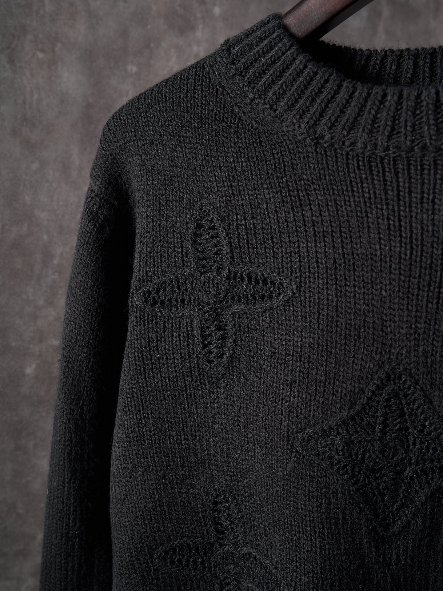Black knit sweater with raised textured monogram graphic