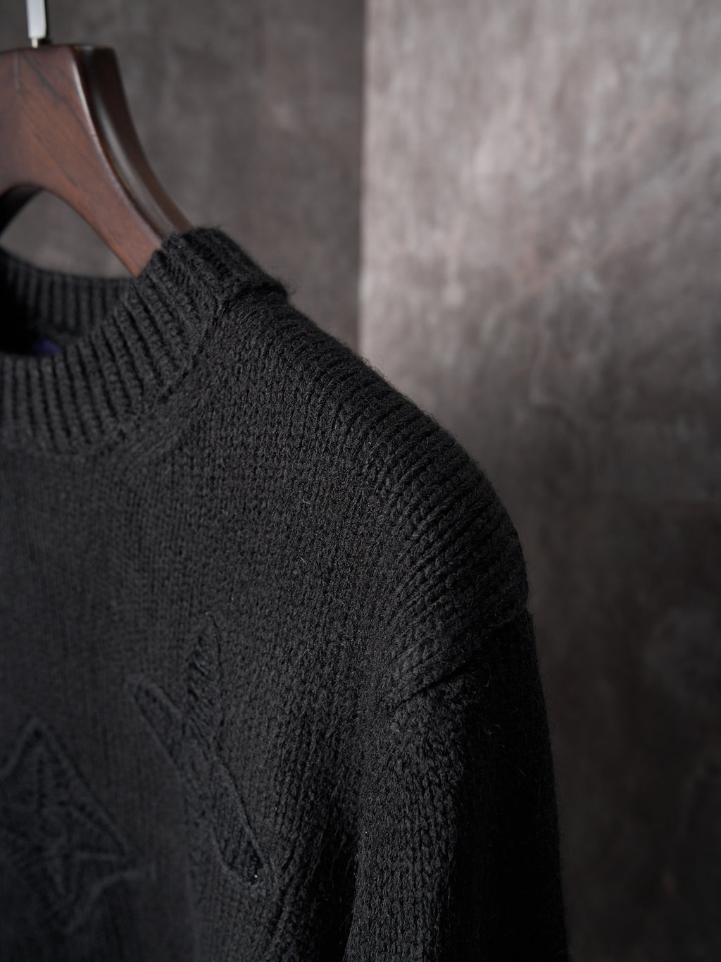 Black knit sweater sleeve with textured monogram pattern