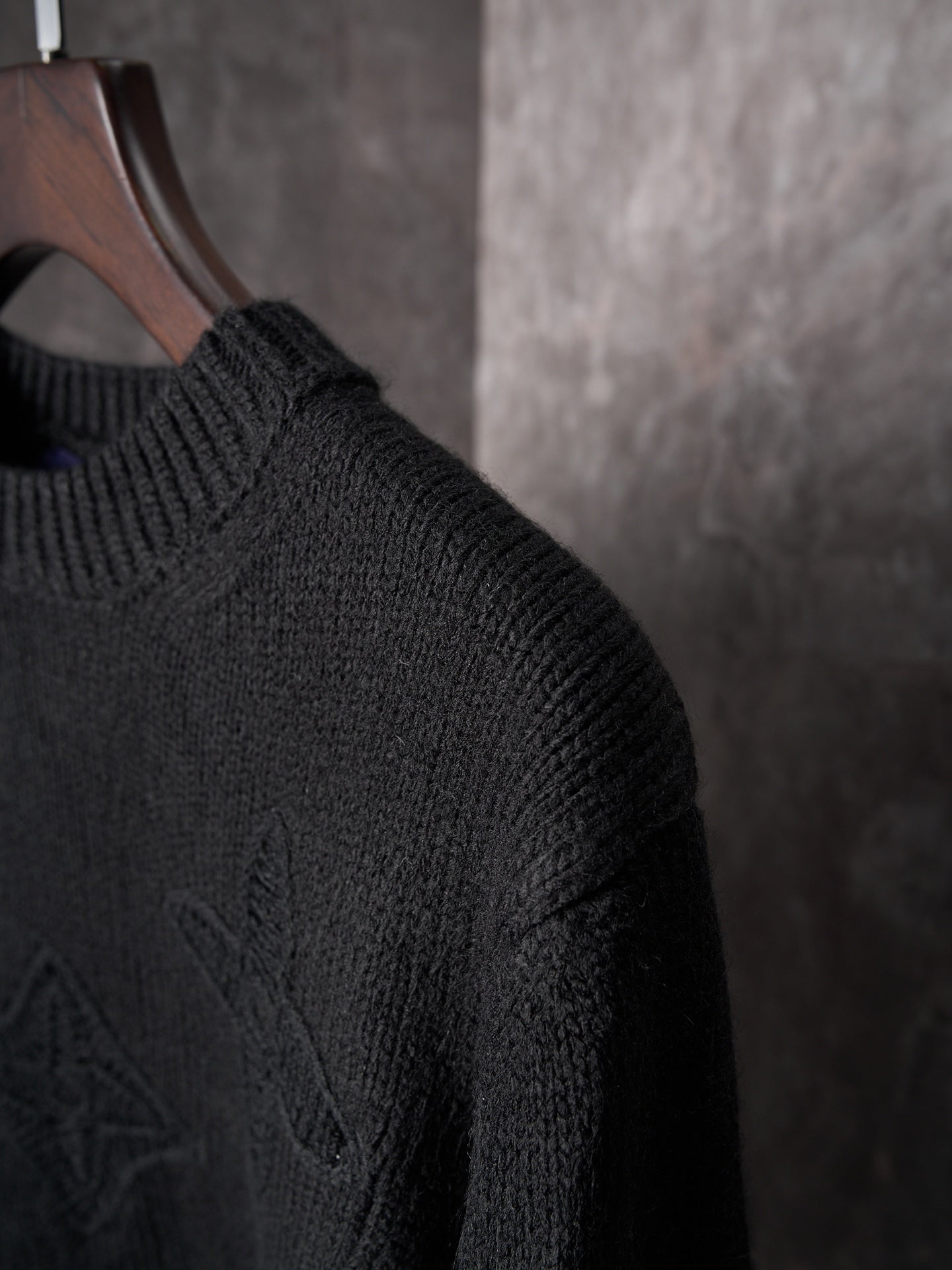 Black knit sweater sleeve with textured monogram pattern