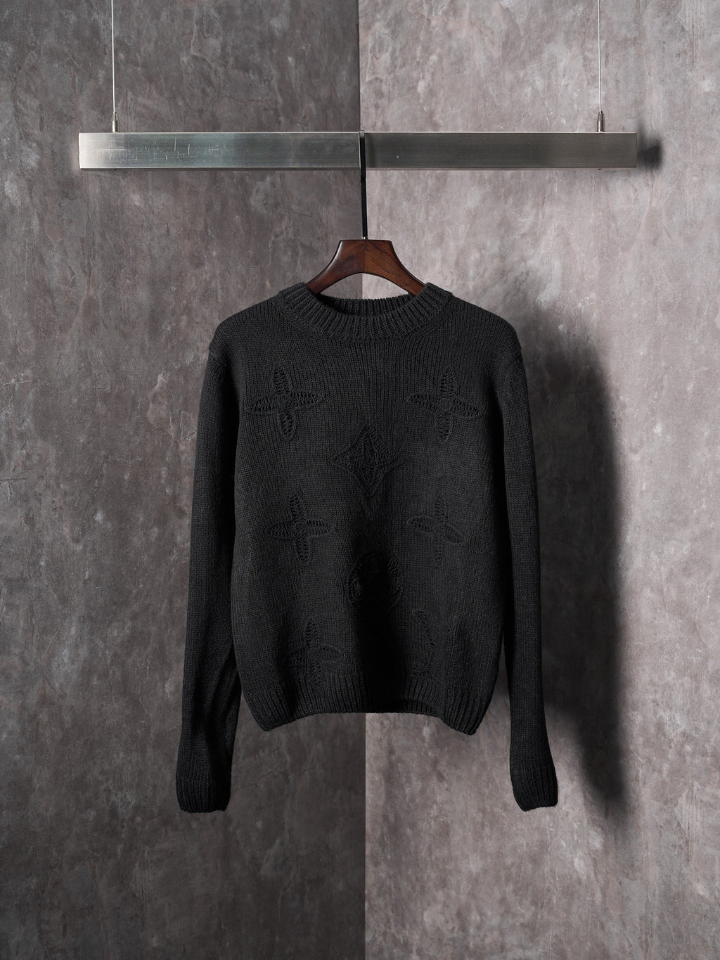 Black knit crewneck sweater with long sleeves and subtle monogram pattern
