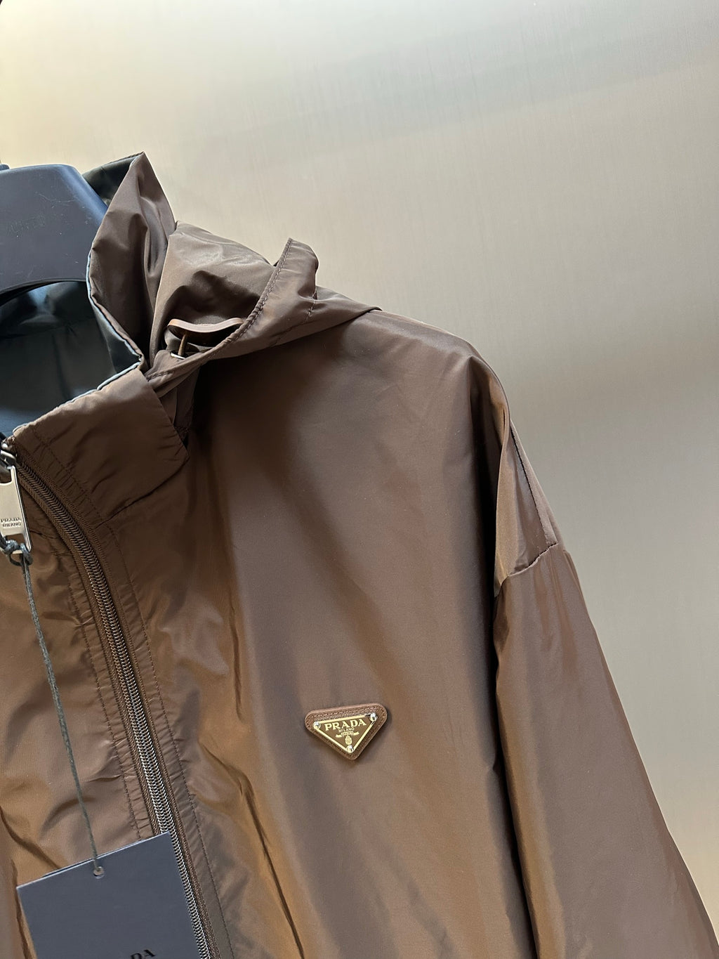 Prada long hooded jacket in dark brown with logo patch and front zipper close-up