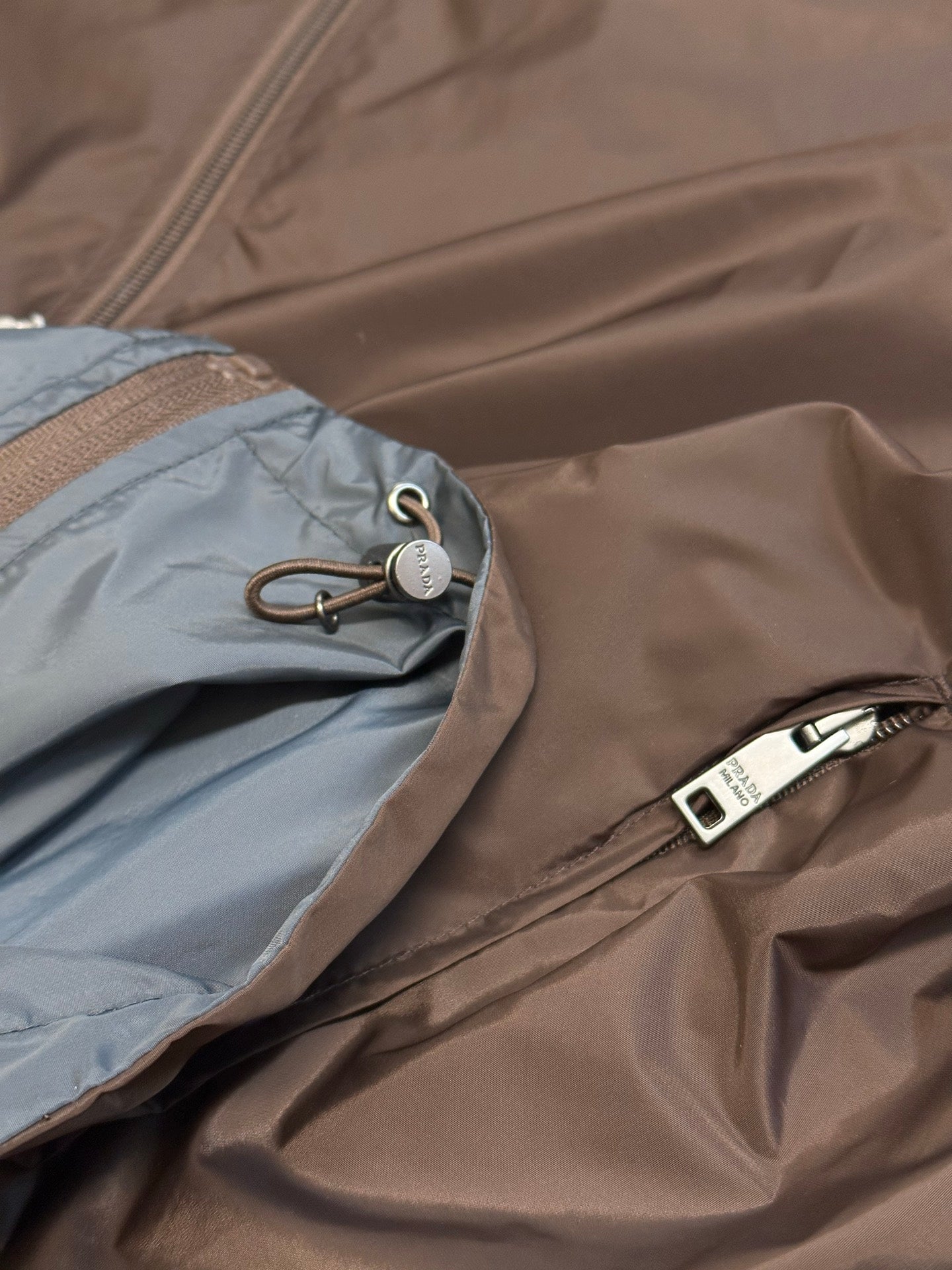 Prada long hooded jacket close-up with contrast inner fabric, toggle drawcord and zipper
