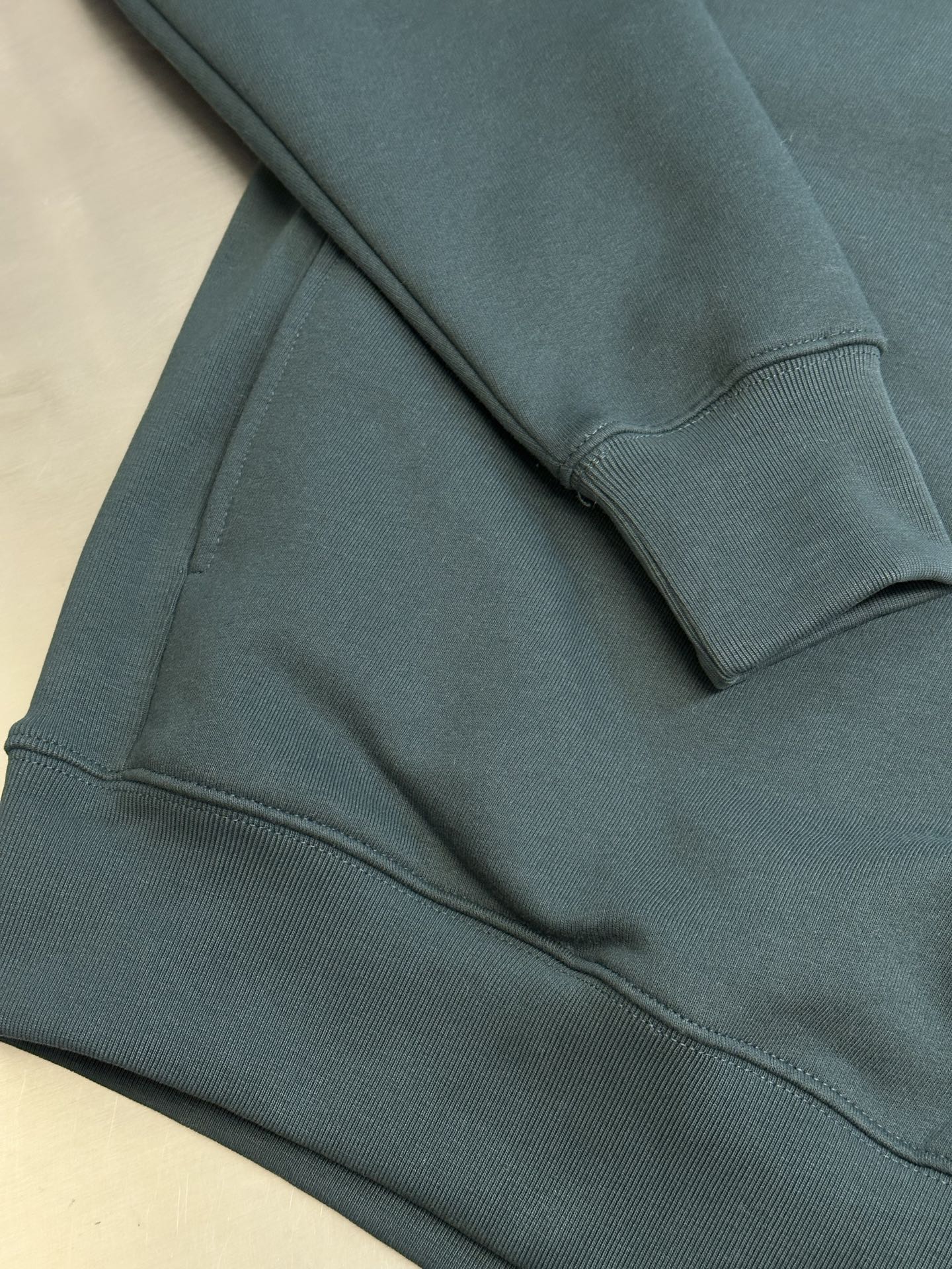 Teal Dior sweatshirt hem and ribbed cuffs with soft knit texture