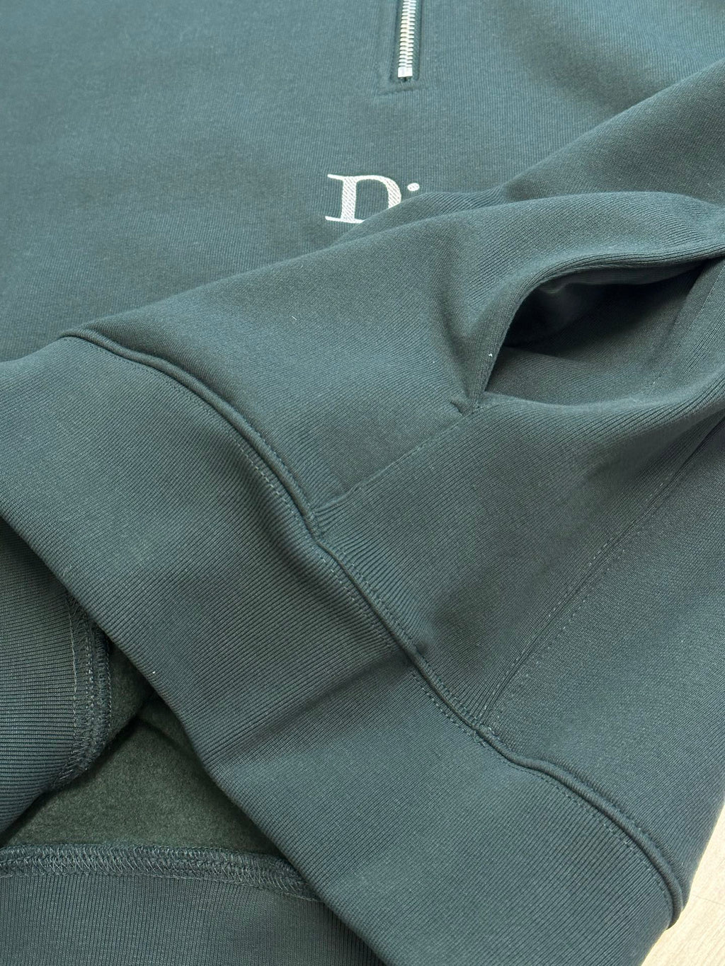 Teal Dior sweatshirt with stitched seam details near logo