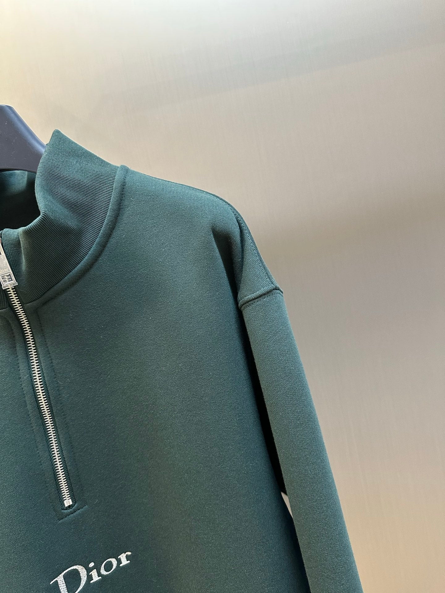 Teal Dior sweatshirt sleeve with quarter-zip placket and zipper teeth
