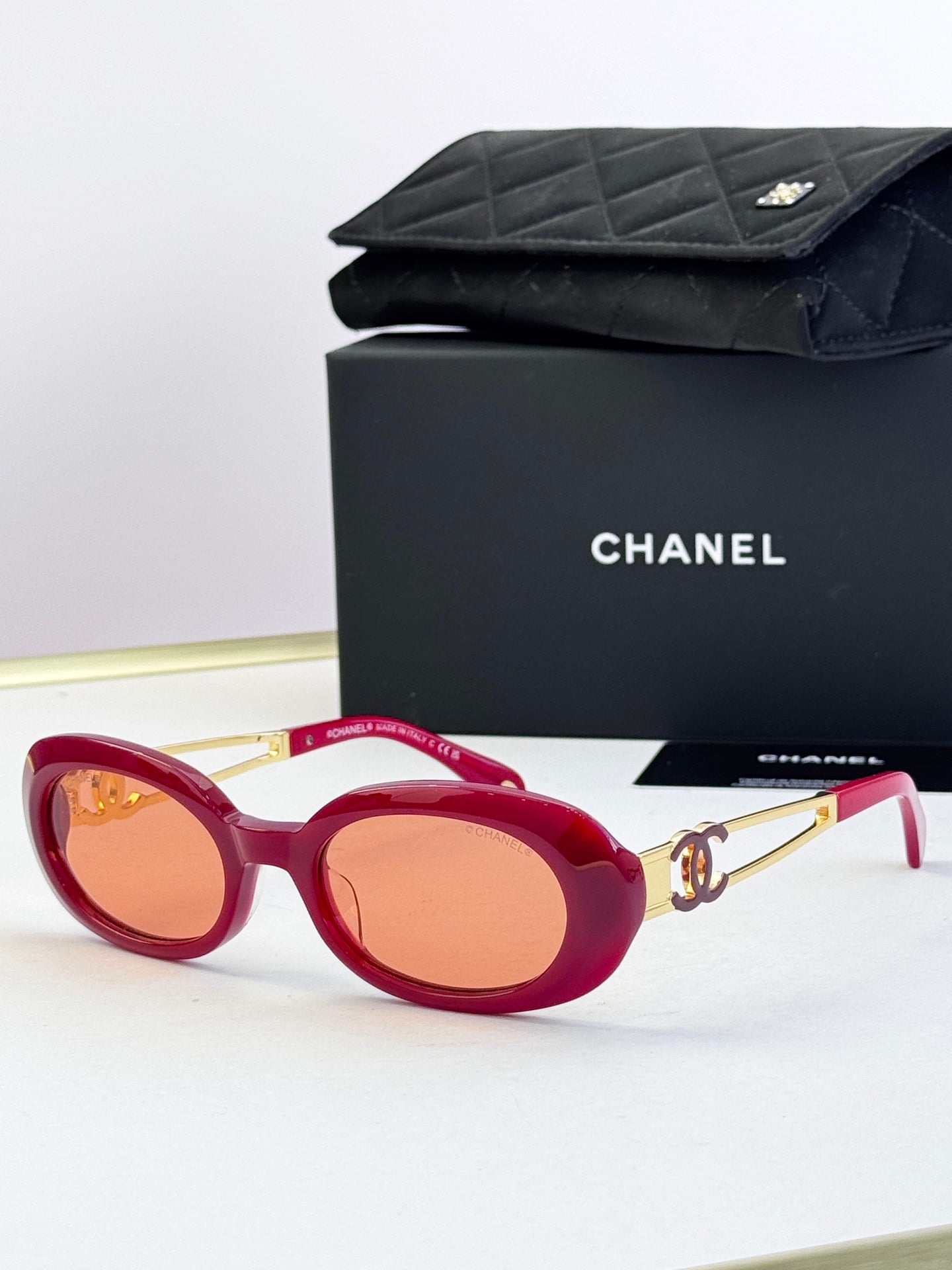 Designer round glasses, red frame with orange lenses, gold logo detail