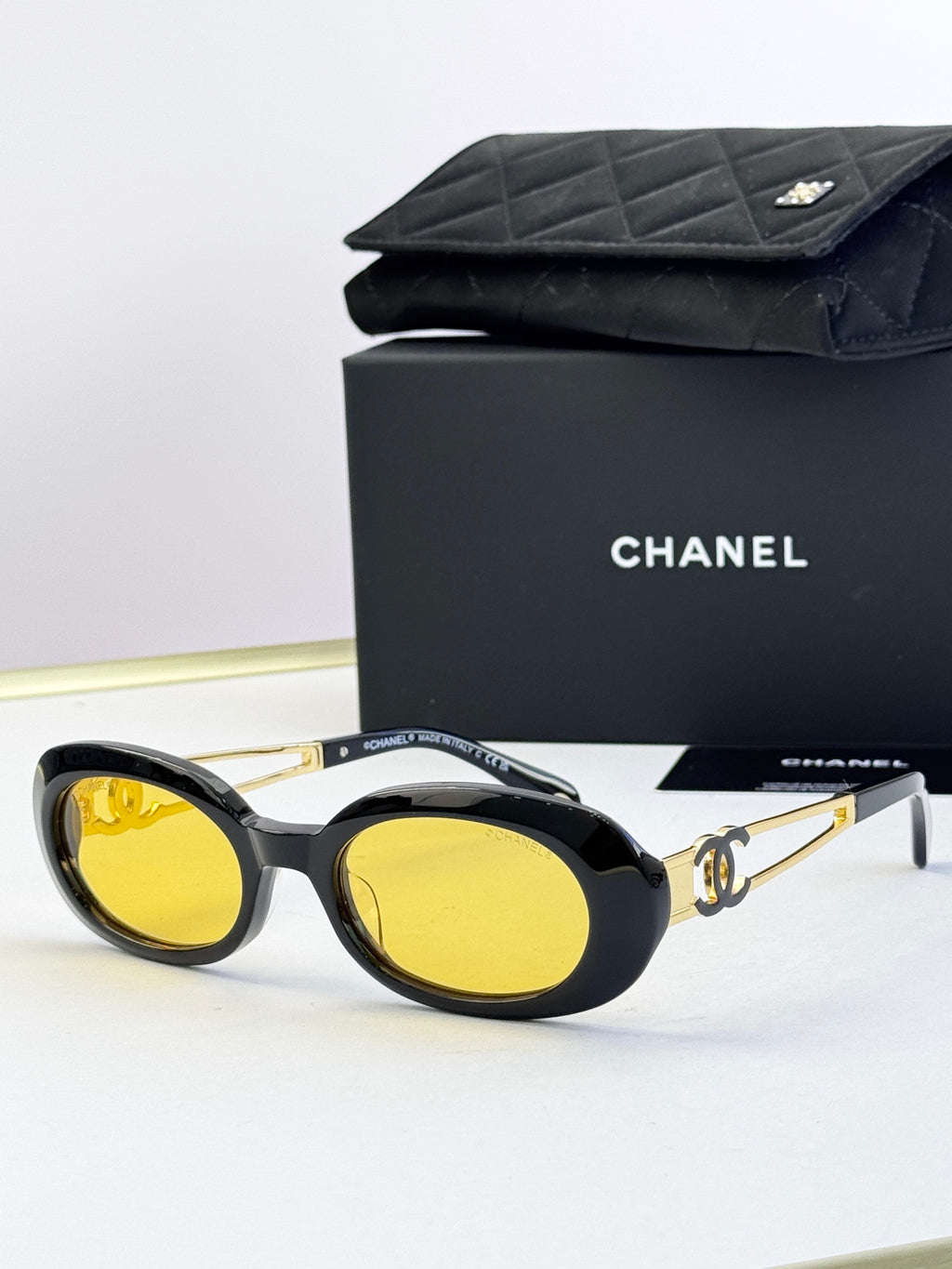 Designer round glasses, black frame with yellow lenses, gold logo detail