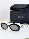 Designer round glasses, black frame with gold logo detail, clear lenses