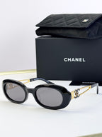 Designer round glasses, black frame with gold logo detail, clear lenses