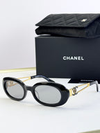 Designer round glasses, black frame with gold logo detail, tinted dark lenses
