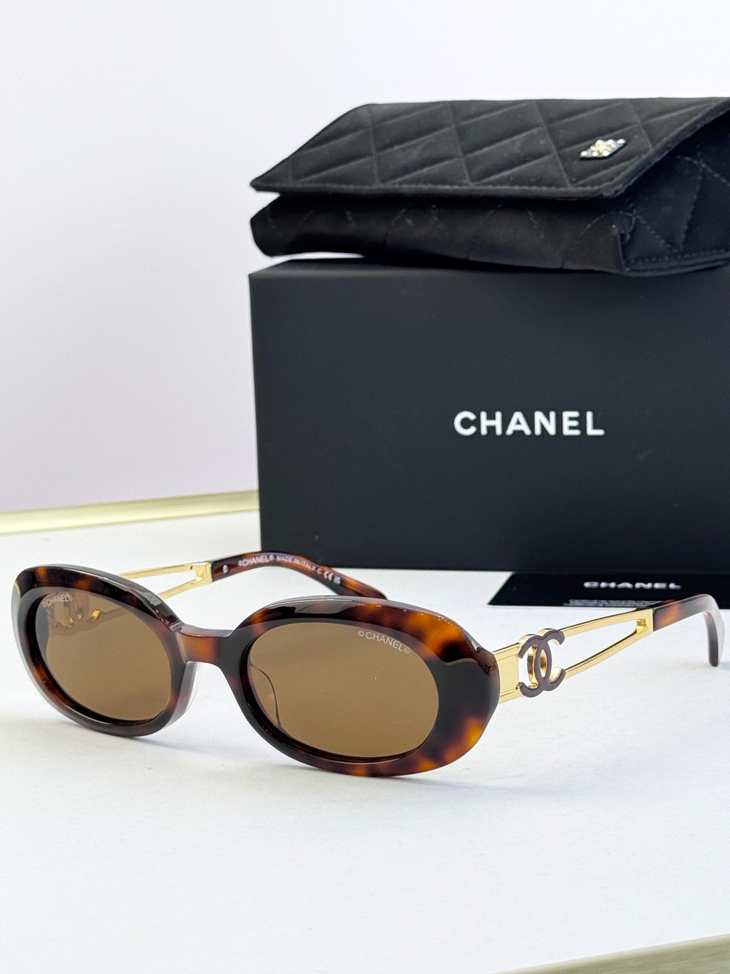 Designer round glasses, tortoiseshell frame with gold logo detail, brown lenses