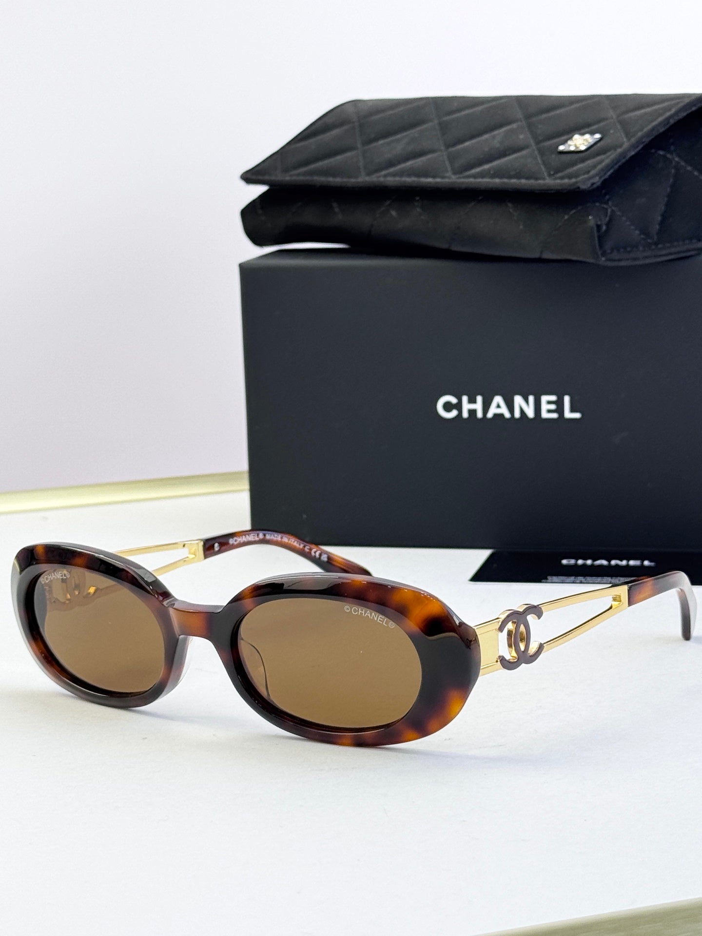 Designer round glasses, tortoiseshell frame with gold logo detail, brown lenses