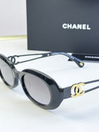 Designer round glasses, black frame with gold CC detail, dark lenses