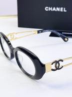 Black oval eyeglasses with gold-tone double-C details on the arms