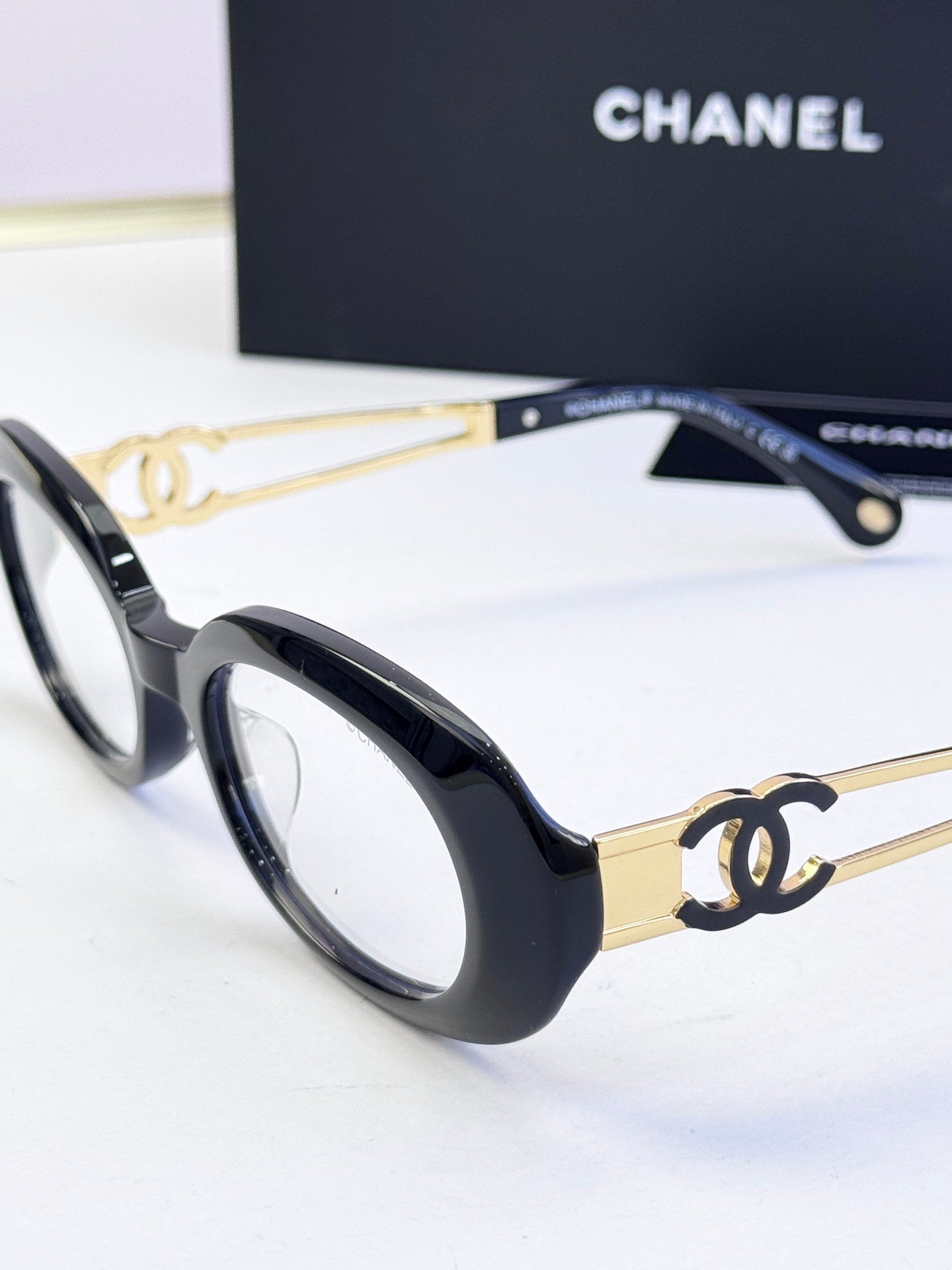 Black oval eyeglasses with gold-tone double-C details on the arms