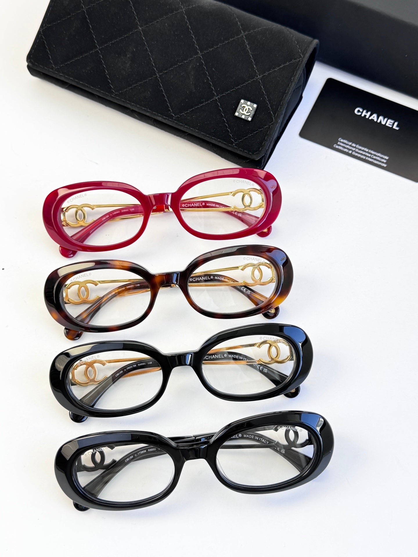 Set of four eyeglasses: red, tortoiseshell, blue, and black with gold details