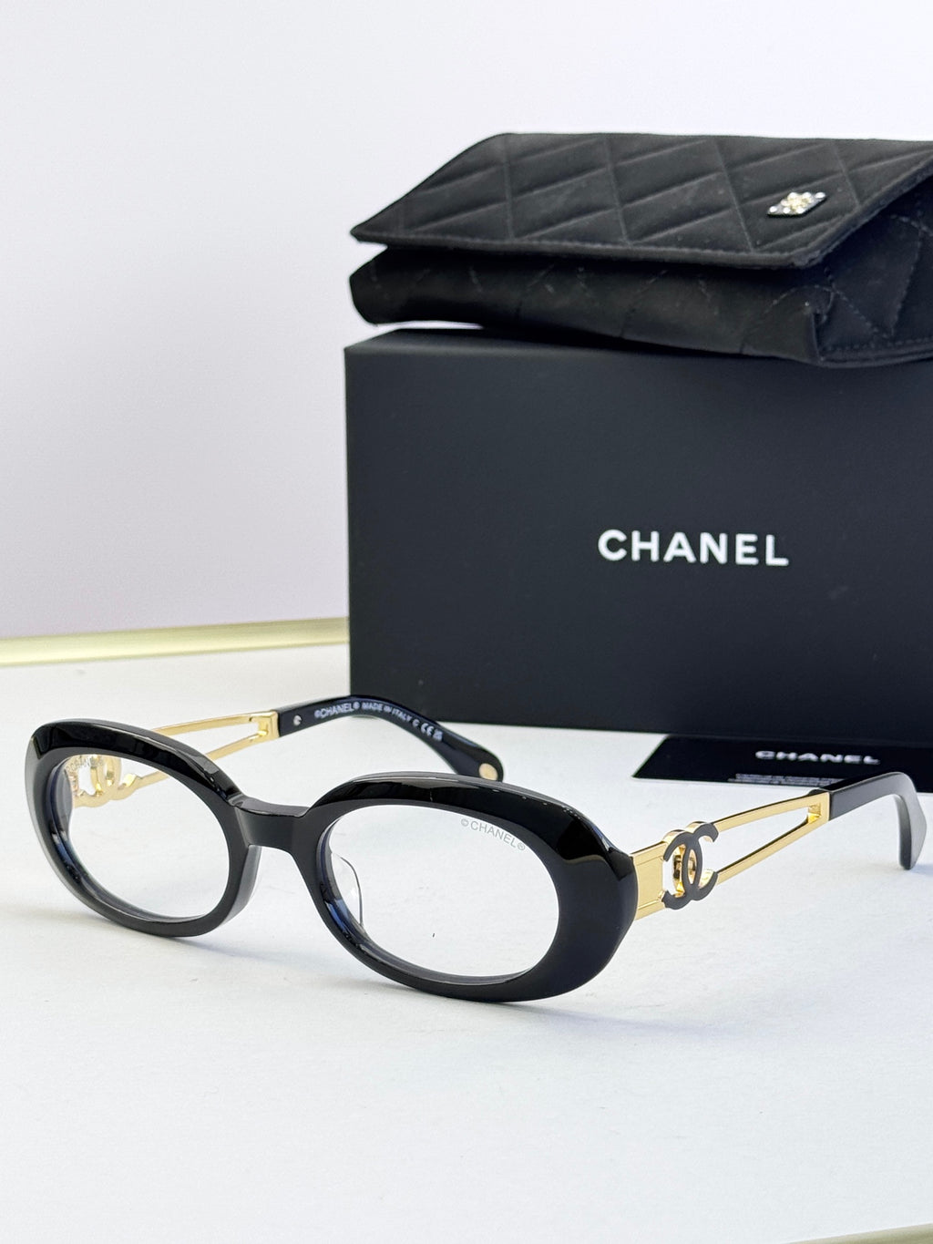Black oval eyeglasses with gold-tone double-C accents on arms