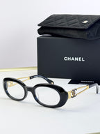 Black oval eyeglasses with gold-tone double-C accents on arms