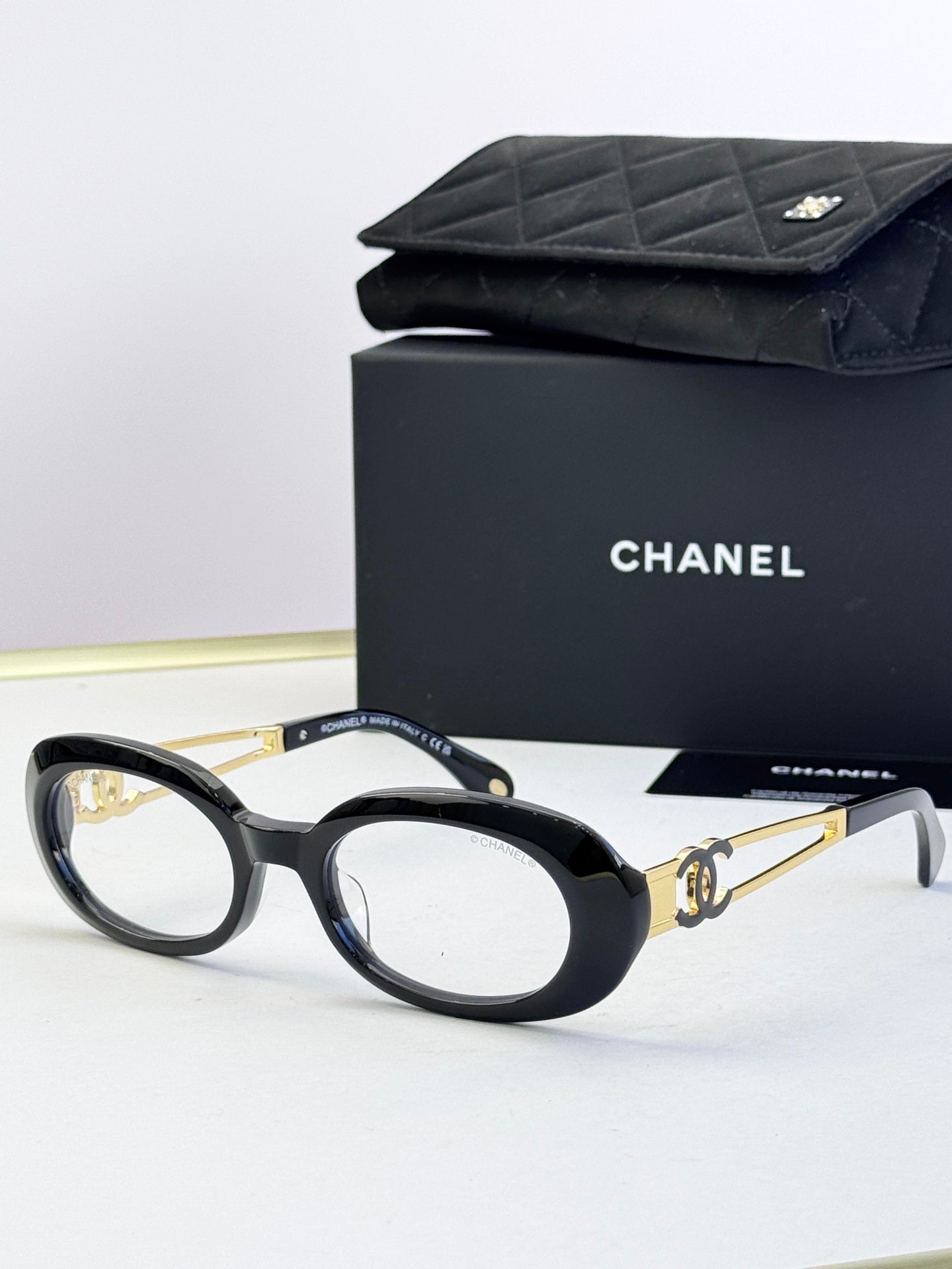 Black oval eyeglasses with gold-tone double-C accents on arms