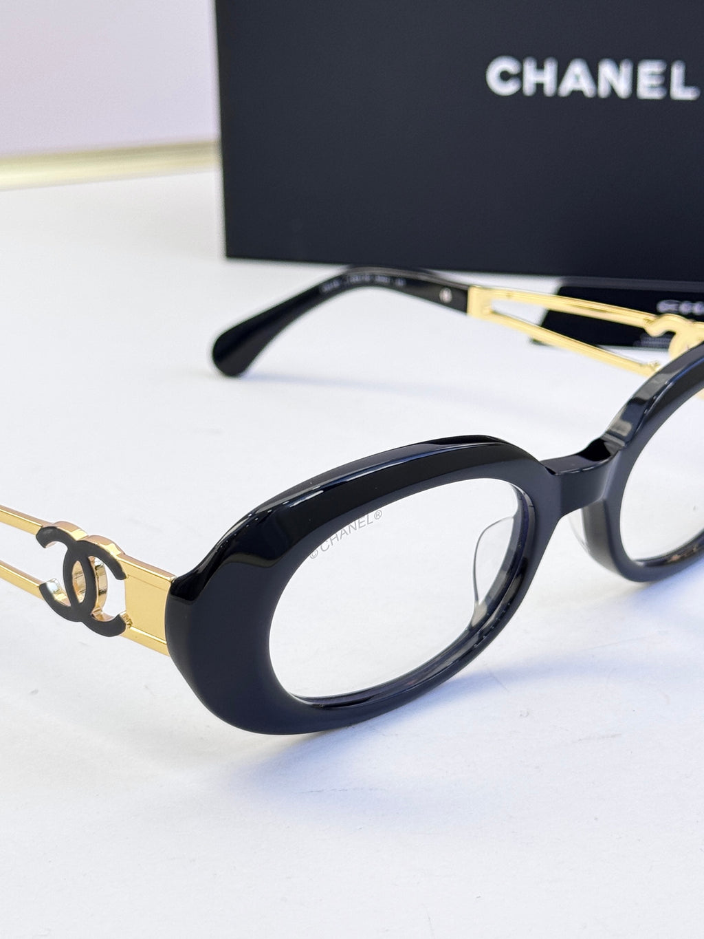 Black oval eyeglasses with gold-tone metal arms and double-C emblem