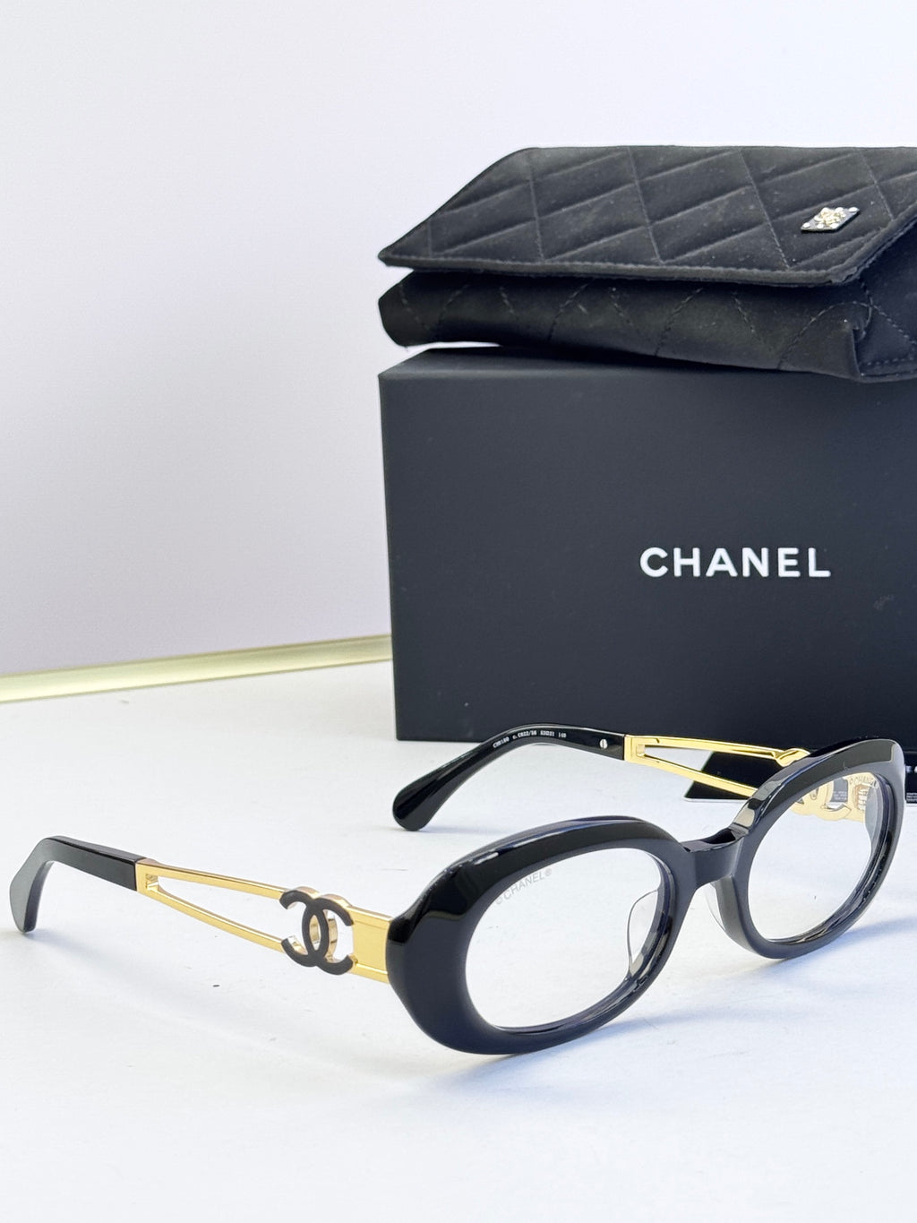 Black-and-gold oval eyeglasses with gold-tone double-C on arms