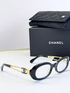 Black-and-gold oval eyeglasses with gold-tone double-C on arms