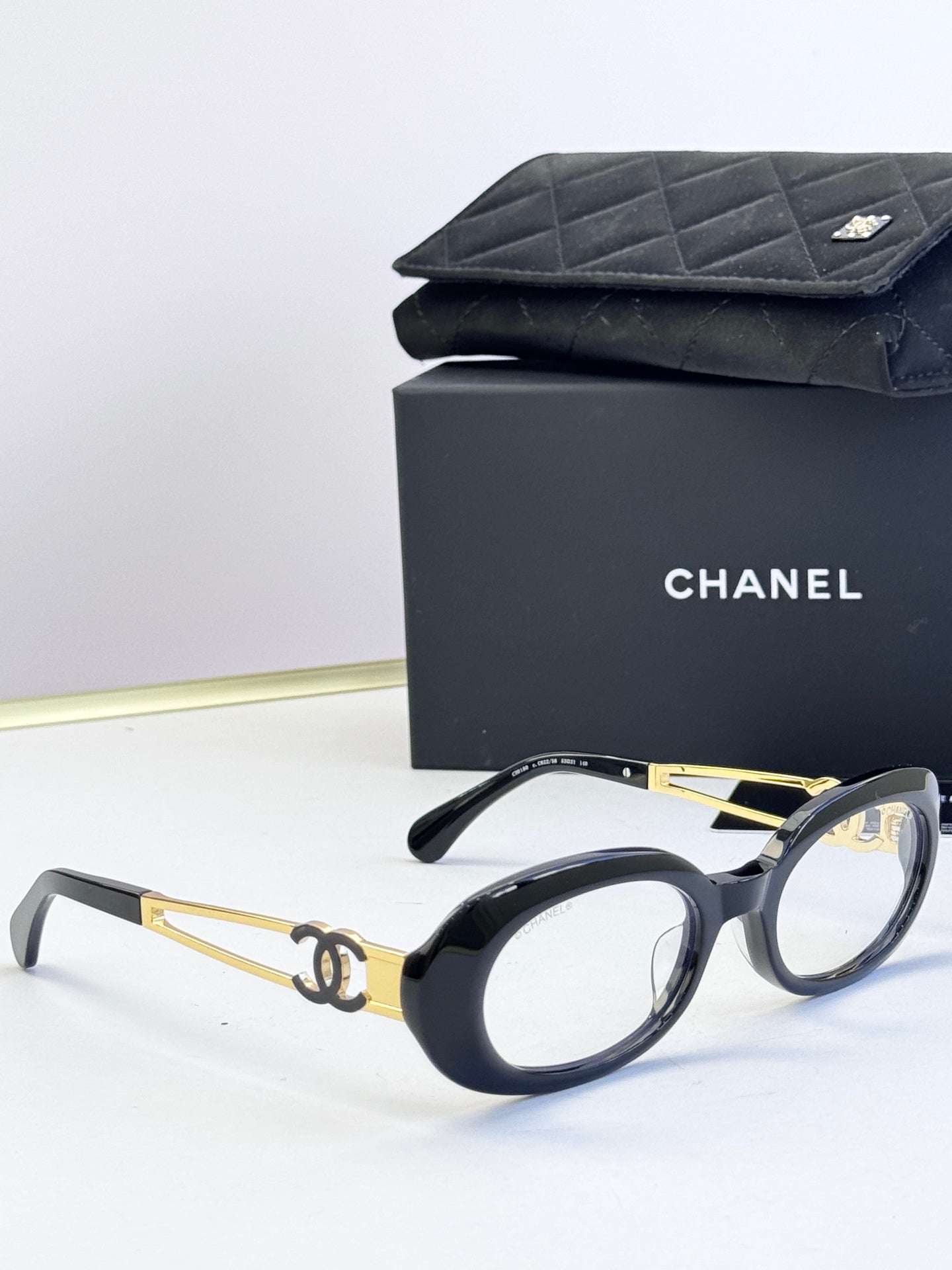 Black-and-gold oval eyeglasses with gold-tone double-C on arms