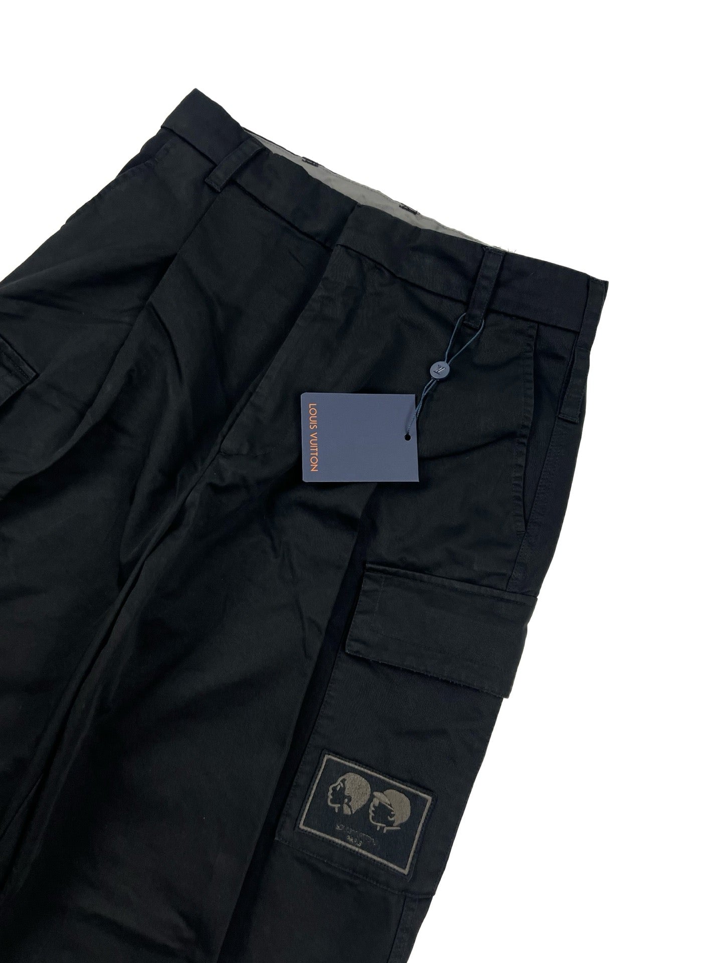 Dark cargo pants waist with belt loops, inner tag, and logo patch on pocket