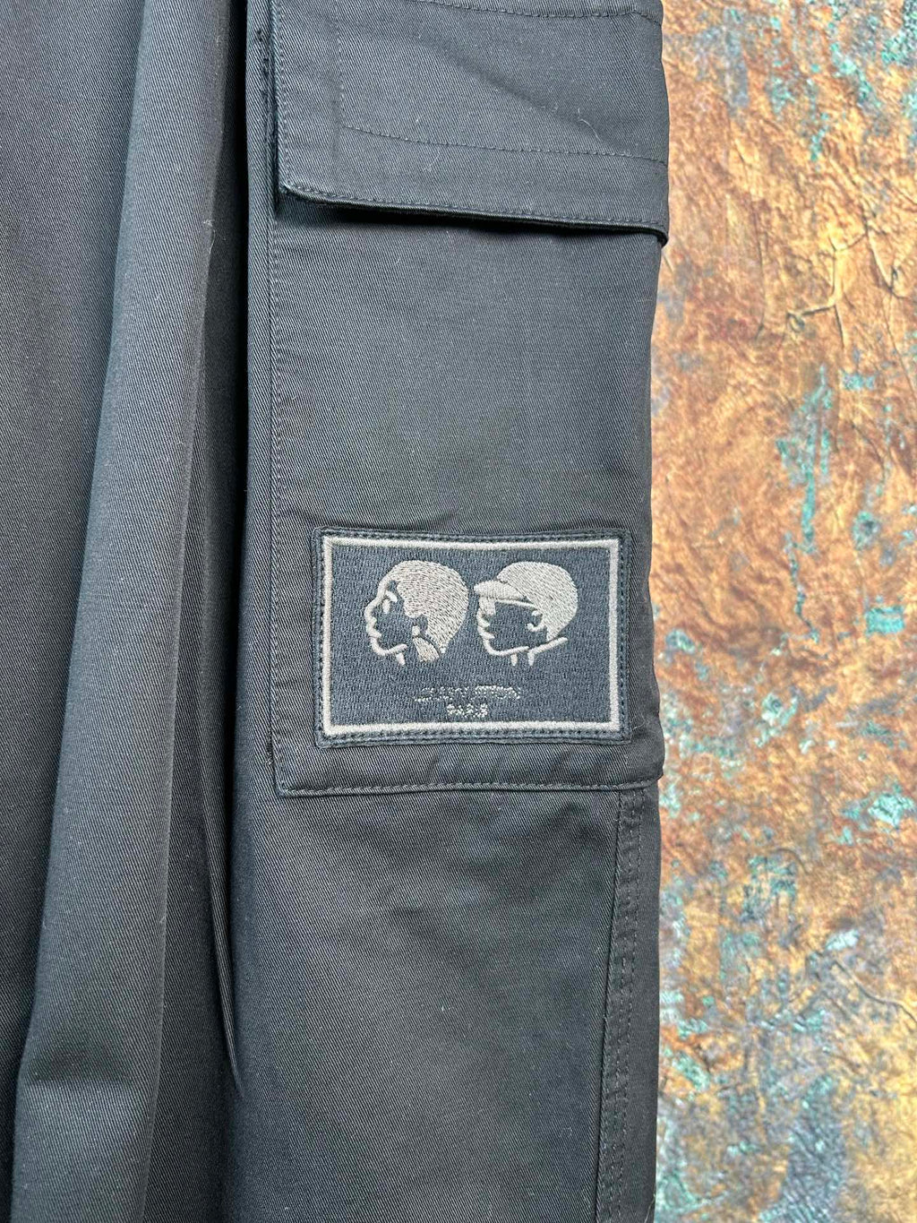 Black cargo pants with embroidered skull patch on a thigh pocket
