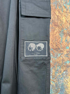 Black cargo pants with embroidered skull patch on a thigh pocket